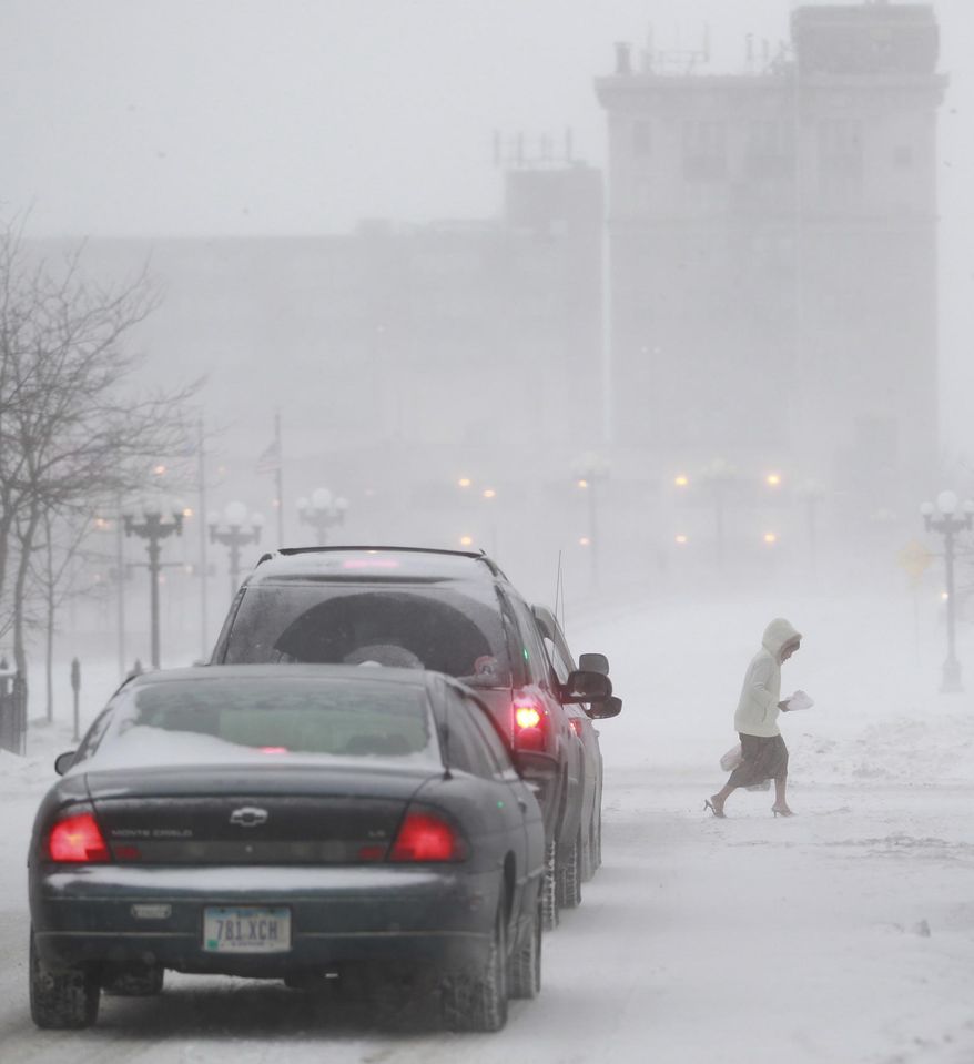 A pedestrian makes her across East 4th Street in Waterloo, Iowa, as rising wind blows snow through downtown Sunday, Jan. 26, 2014. Parts of Iowa xperienced blizzard conditions Sunday before the entire state plunged into bitter cold on Monday. (AP Photo/Waterloo Courier, Brandon Pollock)
