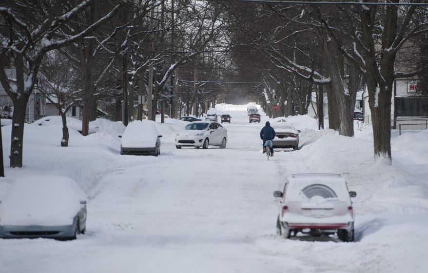 A lone bicyclist makes his way down a snow covered street onon the northeast side Jackson, Mich., on Monday, Jan. 27, 2014. Gusting winds and blowing snow caused whiteout conditions Monday that made travel treacherous on some Michigan roadways, and hundreds of schools closed because of the severe weather. (AP Photo/Jackson Citizen Patriot, J. Scott Park)