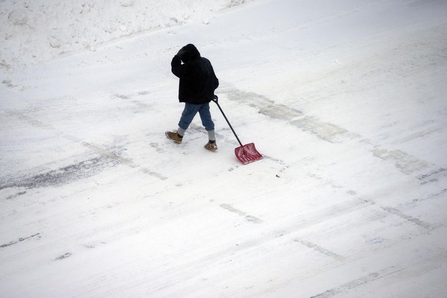 A pedestrian drags a shovel across Indiana 933 along Colfax Avenue on Monday, Jan. 27, 2014, in downtown South Bend. Sub-freezing temperatures and blowing snow returned to the Michiana area yet again as the City of South Bend declared a winter weather emergency. (AP Photo/South Bend Tribune, James Brosher)