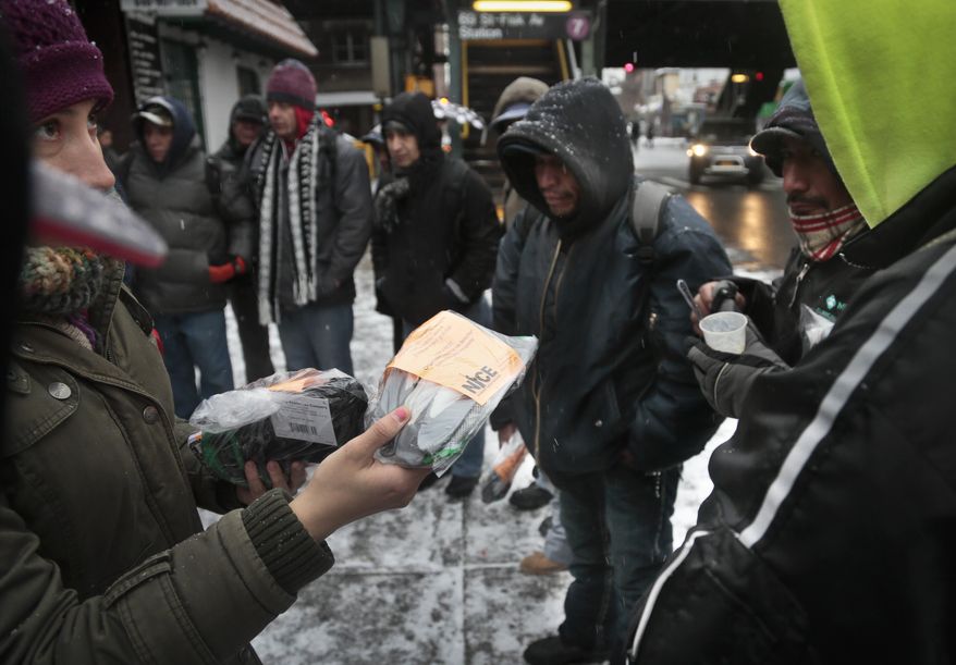 Adriana Escandon, leftr, a coordinator with the New Immigrant Community Empowerment (NICE), distribute work site safety packs to a group of day laborers on Tuesday, Dec. 17, 2013 in Queens, N.Y. NICE provide services for day laborers and the undocumented, including OSHA training, english language classes and legal advice. "Labor laws in this country make it possible that alll these workers have the same rights, regardless of immigration status," said Escandon. (AP Photo/Bebeto Matthews)