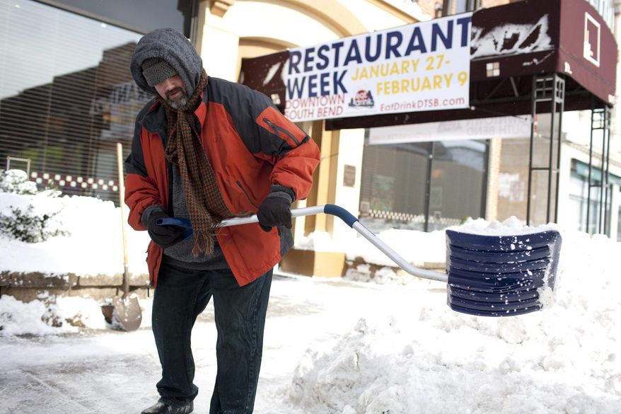 Tom Sheridan, LaSalle Grill's executive chef, shoves a path to the street from the sidewalk outside of the restaurant on Monday, Jan. 27, 2014, in downtown South Bend, Ind. Sub-freezing temperatures and blowing snow returned to the Michiana area yet again as the City of South Bend declared a winter weather emergency. (AP Photo/South Bend Tribune, James Brosher)