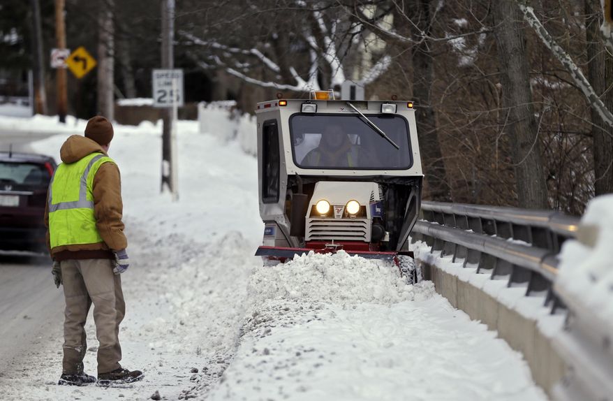 Service department worker Dan Kost plows heavy snow off the sidewalk along Mill St. in Olmsted Falls, Ohio as Ron Karr watches, left, Monday, Jan. 27, 2014. After a weekend of snow, emergency agencies are urging Ohioans to heed safety warnings as another deep freeze blows across the state, bringing temperatures below zero and dangerous wind chills. (AP Photo/Mark Duncan)