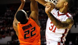 Oklahoma forward D.J. Bennett (31), blocks a shot by Oklahoma State guard Markel Brown during the first half of an NCAA college basketball game in Norman, Okla., Monday, Jan. 27, 2014. (AP Photo/Brody Schmidt)