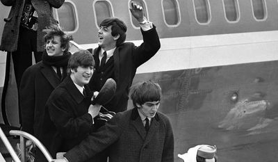 FILE - Britain’s Beatles make a windswept arrival in New York in this  Feb. 7, 1964 file photo, as they step down from the plane that brought them from London, at Kennedy airport. From left to right, Ringo Starr, John Lennon, Paul McCartney and George Harrison. One of the most tumultuous welcomes in pop history is to be recreated next month when UK officials and a tribute band recreate the Beatles’ historic 1964 landing at JFK airport, in a bid to spark interest in Beatles-related tourism to Britain.  (AP Photo, File)