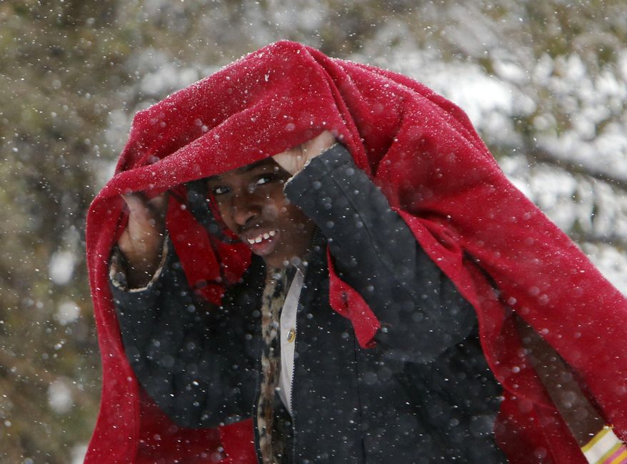 Maya Tilley covers her head from the blowing snow as she walks home from school in Childersburg, Ala. Tuesday Jan. 28, 2014. A fast-moving, unexpectedly severe winter storm blanketed much of Alabama with a treacherous layer of frozen precipitation Tuesday. (AP Photo/Hal Yeager)