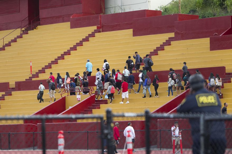 Students are moved to an on-campus stadium at Roosevelt High School after a school shooting, Tuesday, Jan. 28, 2014, in Honolulu. A 17-year-old student was shot by police in a counselor's office after he pulled a knife and cut one of the officers. The student was taken to a local hospital. State Department of Education spokeswoman Donalyn Dela Cruz said the boy showed up Tuesday morning at the school and officials there recognized him as a runaway who was not registered for classes, and called police. (AP Photo/Marco Garcia)