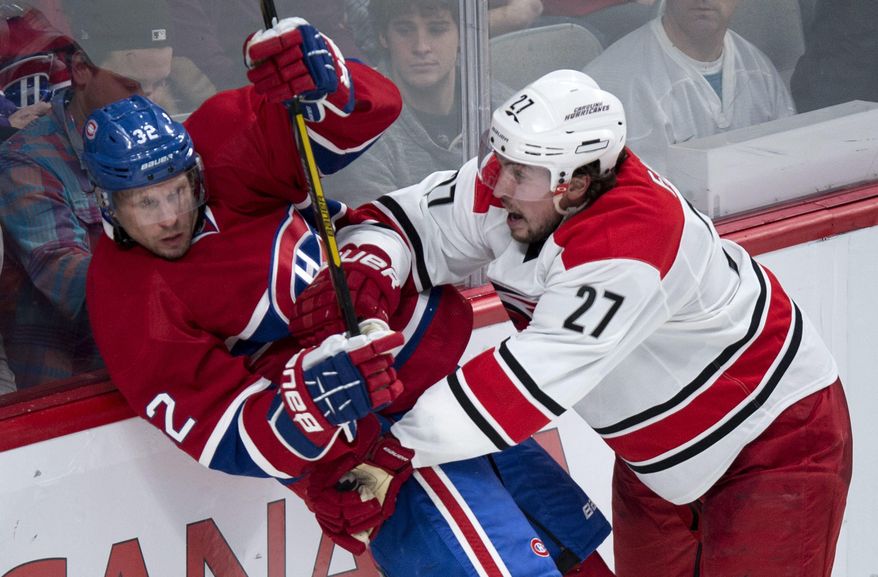 Montreal Canadiens' Travis Moen is checked against the boards by Carolina Hurricanes' Justin Faulk during the third period of an NHL hockey game Tuesday, Jan. 28, 2014, in Montreal. Montreal won 3-0. (AP Photo/The Canadian Press, Paul Chiasson)