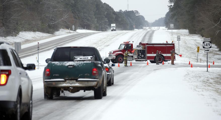 Traffic is rerouted by Braxton Fire Department fire fighters from U.S. Route 49 near Braxton, Miss., because sections of the road are closed as ice and snow flurries cause difficult driving conditions, Tuesday, Jan. 28, 2014. A severe winter storm hit Mississippi and the South bringing ice, snow and below freezing temperatures. (AP Photo/Rogelio V. Solis)