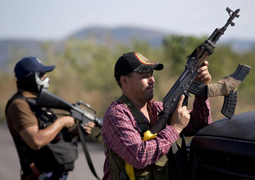FILE - In this Jan. 14, 2014 file photo, armed men belonging to the Self-Defense Council of Michoacan, (CAM), stand guard at a checkpoint at the entrance of Antunez, Mexico. The government announced that it had reached a deal with vigilante leaders to incorporate the armed civilian groups into old and largely forgotten quasi-military units called the Rural Defense Corps. Vigilante leaders met Tuesday Jan. 28, with government officials to hash out details of the agreement. (AP Photo/Eduardo Verdugo, file)
