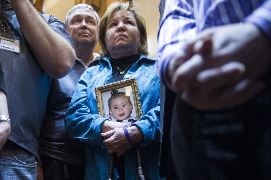 Medical marijuana advocate Barbara Kutchback, of Monroe, Ga., holds a photo of her 3-year-old granddaughter as she listens to other advocates tell of their children's suffering, after a bill to legalize marijuana for medicinal purposes was introduced in the State House chamber on Tuesday, Jan. 28, 2014, in Atlanta. Kutchback's granddaughter suffers from a rare epilepsy disease and they believe marijuana can help relieve her suffering. (AP Photo/John Amis)