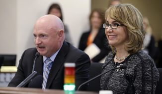 Former Arizona Congresswoman Gabrielle Giffords, right, smiles briefly as her husband, retired NASA space shuttle commander Mark Kelly, testifies before a Washington state House panel Tuesday, Jan. 28, 2014, in Olympia, Wash. Giffords, who survived a 2011 shooting, testified before the panel considering an initiative to expand firearm background checks in the state, telling lawmakers that &amp;quot;the nation is counting on you.&amp;quot; With Kelly sitting next to her, Giffords spoke slowly and briefly to the panel that was taking public testimony on Initiative 594. (AP Photo/Elaine Thompson)