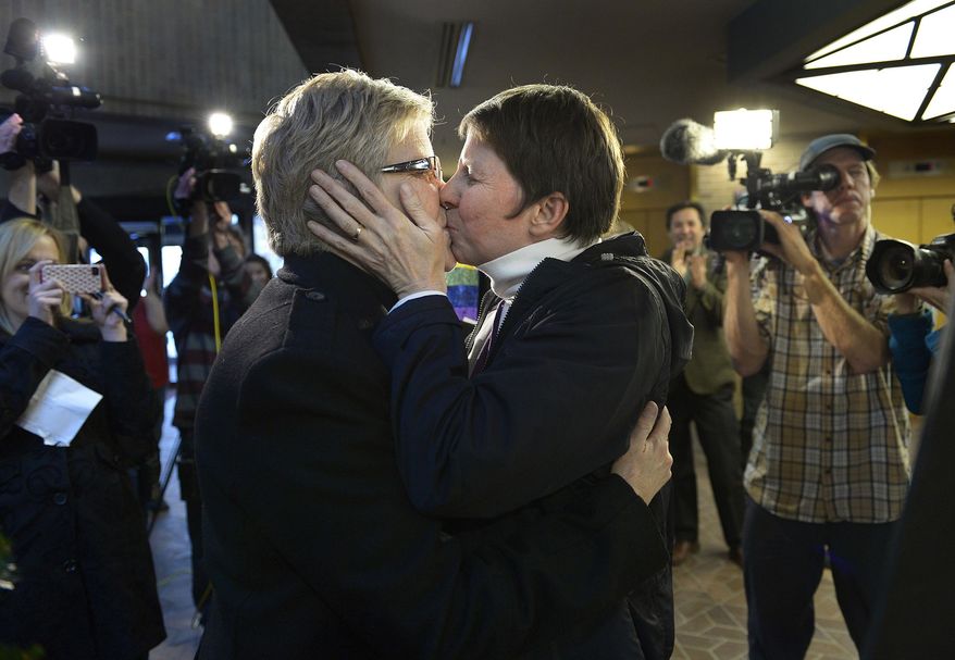 FILE - In this Dec. 20, 2013, file photo, Laurie Wood, left, and Kody Partridge, kiss after being told they are officially married by the Rev. Curtis L. Price in the lobby of the Salt Lake County offices, in Salt Lake City. Opponents and supporters of gay marriage are planning twin rallies at the Utah State Capitol on Tuesday evening. The opposing gatherings are the latest square-off over gay marriage, an issue that took Utah by surprise over the past month. (AP Photo/The Salt Lake Tribune, Scott Sommerdorf, File)