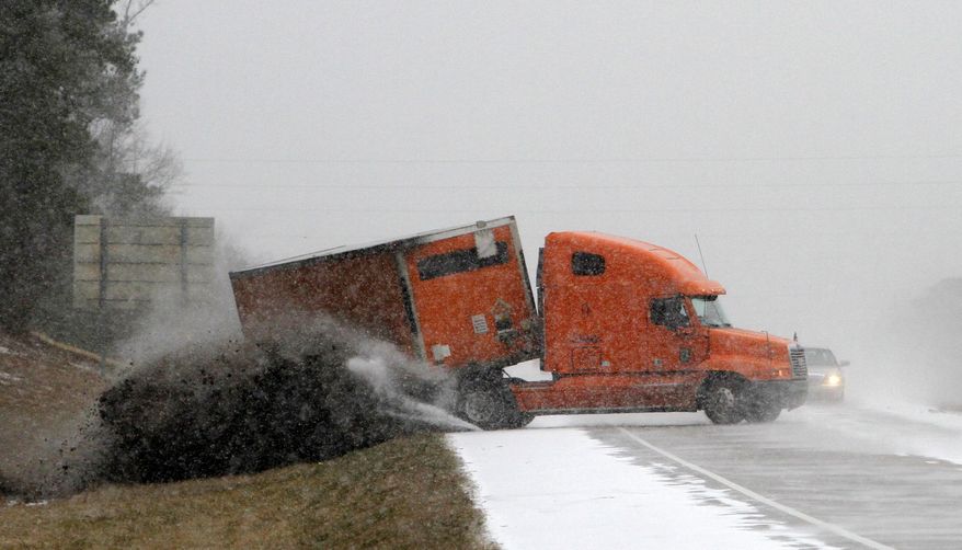 A truck slides off the roade as it tries to avoid another wrecked truck as snow begins to accumulate on I-65 nerar Clanton, Ala., Tuesday, Jan. 28, 2014. The southern half of Alabama shut down Tuesday because of a rare storm that left a slippery layer of ice and snow across a region unaccustomed to dealing with the wintry threat. (AP Photo/Butch Dill)