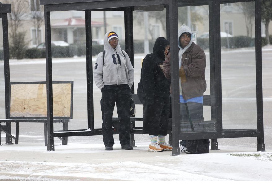 People wait in a bus shelter in north Jackson, Miss., Tuesday, Jan. 28, 2014 as ice and snow flurries cause difficult driving conditions. A severe winter storm is expected to hit the state bringing ice and snow to the Gulf Coast. (AP Photo/Rogelio V. Solis)