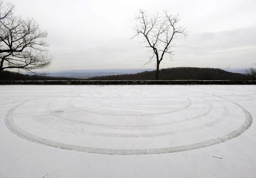A circle made by a turning car leaves a pattern in the snow as a light snow falls over Huntsville, Ala., Tuesday, Jan. 28, 2014. A fast-moving, unexpectedly severe winter storm blanketed much of Alabama with a treacherous layer of frozen precipitation Tuesday, causing multiple wrecks, stranding hundreds of children in schools and coating palm trees with ice at the beach. (AP Photo/Eric Schultz, AL.com)