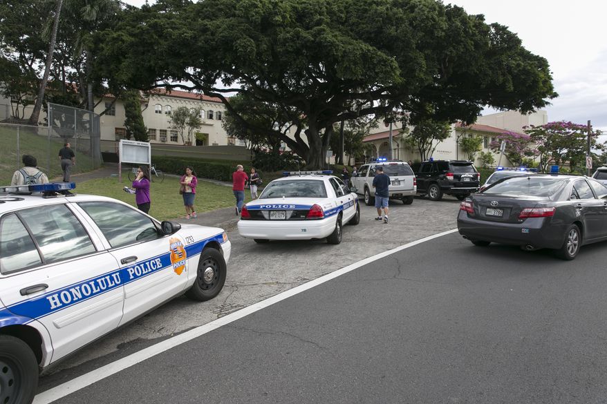 Police respond to the campus of Roosevelt Hight School, after a shooting, Tuesday, Jan. 28, 2014, in Honolulu. A police officer shot a 17-year-old runaway in the wrist at the high school after the teen cut one officer with a knife and punched two others, authorities said. State Department of Education spokeswoman Donalyn Dela Cruz said the boy showed up Tuesday morning at Roosevelt High School. Officials there recognized him as a runaway who was not registered for classes, and called police. Maj. Richard Robinson, commander of the Honolulu Police Department’s Criminal Investigations Division, said the boy lunged at officers who arrived at the public high school near downtown Honolulu and tried to take him into custody. (AP Photo/Marco Garcia)