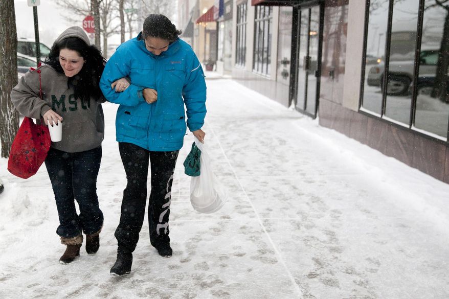 In this Monday, Jan. 27, 2014 photo, Rebecca Winklepleck, right, holds onto Melanie Whiting, as they brave blowing snow in downtown Jackson, Mich. (AP Photo/The Jackson Citizen Patriot, Michelle Tessier)