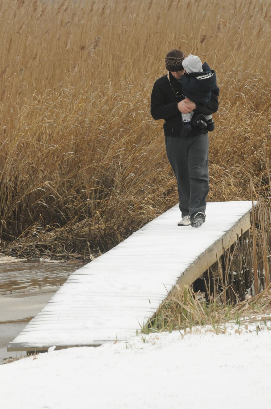 Josh Watson walks on the dock with his son Parker at the end of Crofter's Court in Leland, N.C. Wednesday, Jan. 29, 2014. A winter storm left the area cover in a blanket of ice and snow. (AP Photo/The Star-News, Ken Blevins)