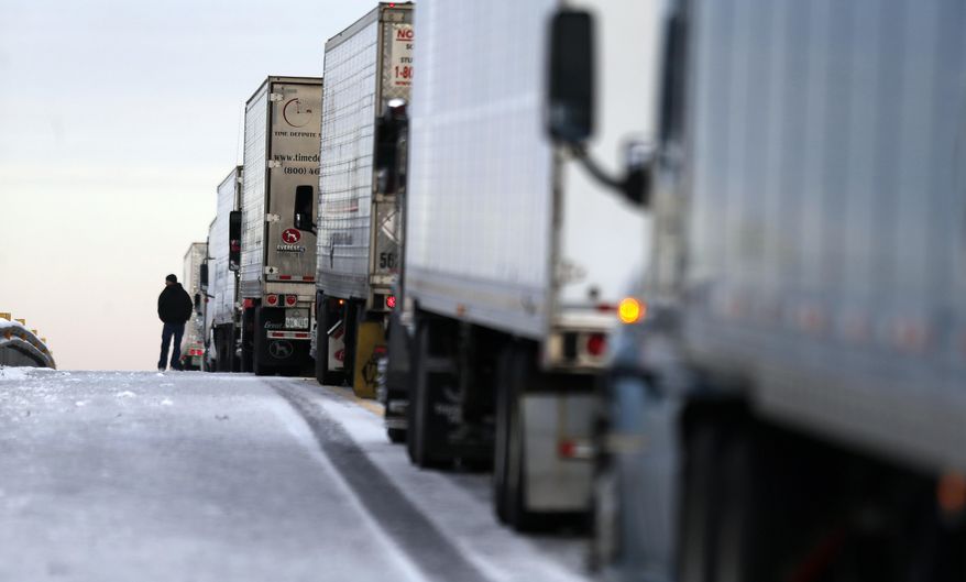 A man stands on the frozen roadway as he waits for traffic to clear along Interstate 75 Wednesday, Jan. 29, 2014, in Macon, Ga. A winter storm dumped snow and covered parts of the state with ice. Gov. Nathan Deal said early Wednesday that the National Guard was sending military Humvees onto Atlanta's snarled freeway system in an attempt to move stranded school buses and get food and water to people. (AP Photo/John Bazemore)