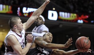 Cincinnati&#39;s Troy Caupain (10) passes the ball as he cuts between Temple&#39;s Dalton Pepper, left, and Anthony Lee during the second half of an NCAA college basketball game on Sunday, Jan. 26, 2014, in Philadelphia. Cincinnati won 80-76. (AP Photo/Michael Perez)
