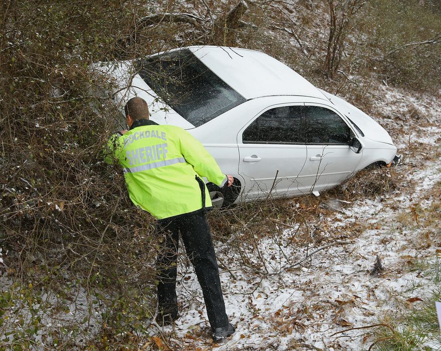 A Rockdale Sheriff deputy checks on a crashed vehicle off Interstate 20 West near Conyers, Ga., Tuesday, Jan. 28, 2014. A winter storm that would probably be no big deal in the North all but paralyzed the Deep South on Tuesday, bringing snow, ice and teeth-chattering cold, with temperatures in the teens in some places. (AP Photo/Atlanta Journal-Constitution, Curtis Compton)
