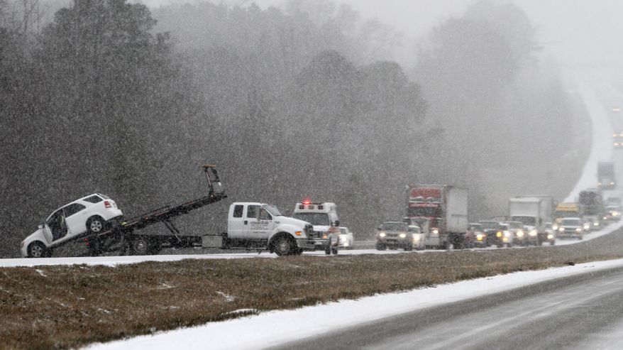 Traffic backs up as a wrecker pulls a car out of a ditch on Interstate 65 during an unusual snow Tuesday, Jan. 28, 2014, in Clanton, Ala. A rare storm left a slippery layer of ice and snow across a region unaccustomed to dealing with the wintry threat. (AP Photo/Butch Dill)