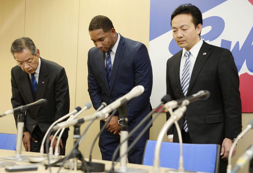 Yakult Swallows slugger Wladimir Balentien, center, bows during a press conference in Tokyo Wednesday, Jan. 29, 2014. Balentien has apologized to his fans, several days after pleading not guilty to domestic violence charges in Florida. As is the custom in Japan, Balentien bowed deeply and then apologized Wednesday to his fans and teammates for the actions that led to his arrest on Jan. 13. (AP Photo/Kyodo News) JAPAN OUT, MANDATORY CREDIT