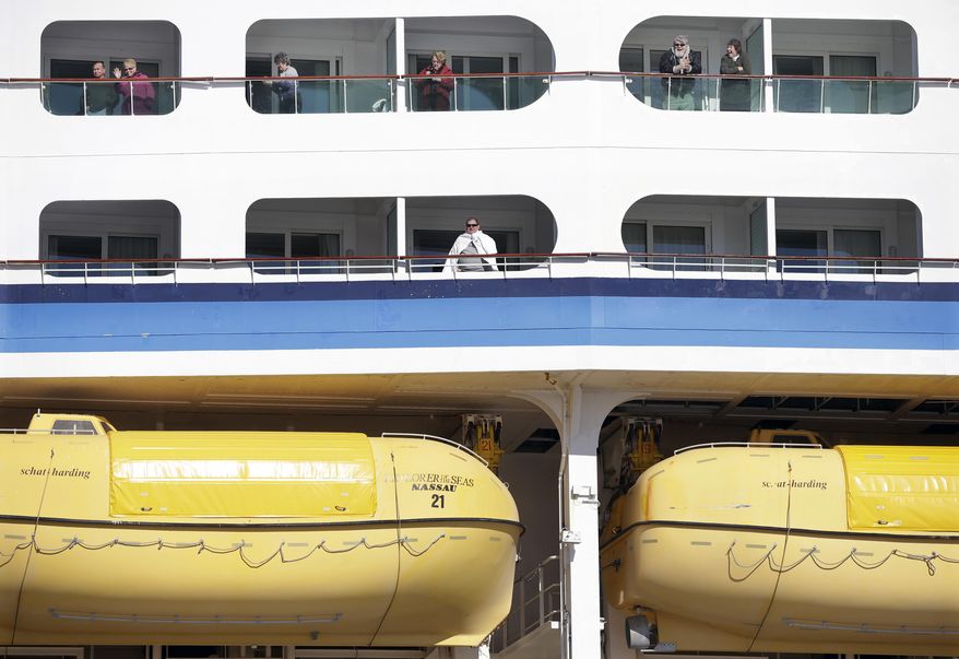 People look out from the Explorer of the Seas cruise ship as it docks at a berth, Wednesday, Jan. 29, 2014, in Bayonne, N.J. The number of passengers and crew reported stricken ill on the cruise ship has risen to nearly 700. The U.S. Centers for Disease Control and Prevention said Wednesday its latest count puts the number of those sickened aboard the Explorer of the Seas at 630 passengers and 54 crew members. (AP Photo/Mel Evans)