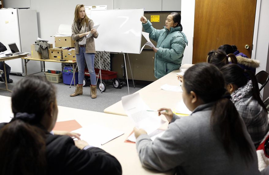 Volunteer teacher Alicia Soppe, left, with help from interpreter Liberata Aung, right, teach the war of 1812 during a Burmese civic class made possible by U.S. Committee for Refugees and Immigrants office at First United Methodist Church Wednesday, Jan. 29, 2014, in Waterloo, Iowa. (AP Photo/Waterloo Courier, Matthew Putney)