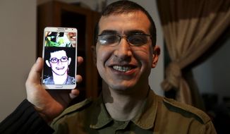 In this Sunday, Jan. 26, 2014 photo, director Majed Jundiyeh holds a mobile phone to compare the image of Gilad Schalit to the likeness of actor Mahmoud Karira, who will play the character of Shalit in a movie being made in Gaza called, &#39;&#39;Losing  Shalit,&amp;quot; in Gaza City. &amp;quot;Losing Schalit,&amp;quot; currently being filmed in the blockaded territory, is the first of a planned three-part series about the 2006 capture of Israeli soldier Gilad Schalit by gunmen allied with the Islamic militant Hamas movement. Parts two and three will depict Schalit&#39;s time in captivity and his 2011 swap for hundreds of Palestinian prisoners held by Israel. (AP Photo/Hatem Moussa)