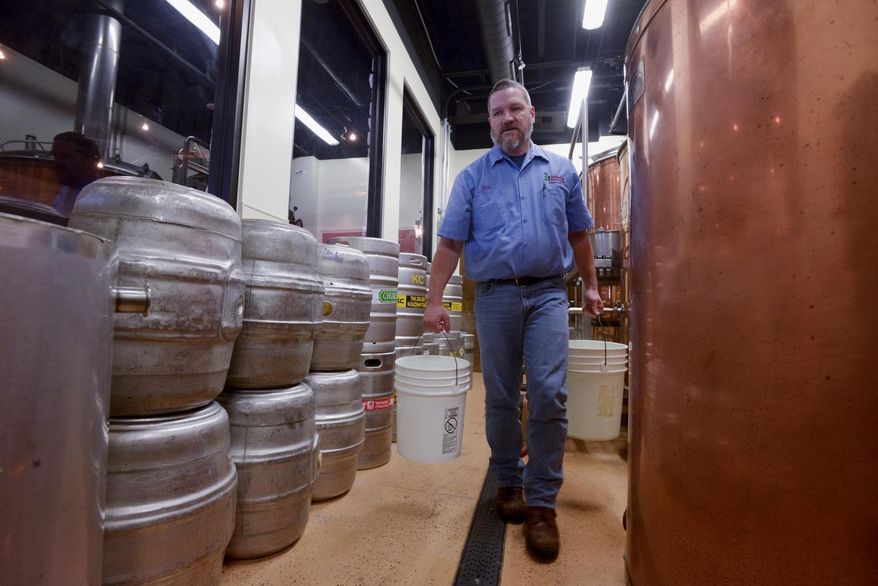In this Dec. 10, 2013 photo, Ken McMullen, brewmaster at the Hopvine Brewing Co. in Aurora, Ill., carries buckets while cleaning the tanks. (AP Photo/Daily Herald, Mark Black)