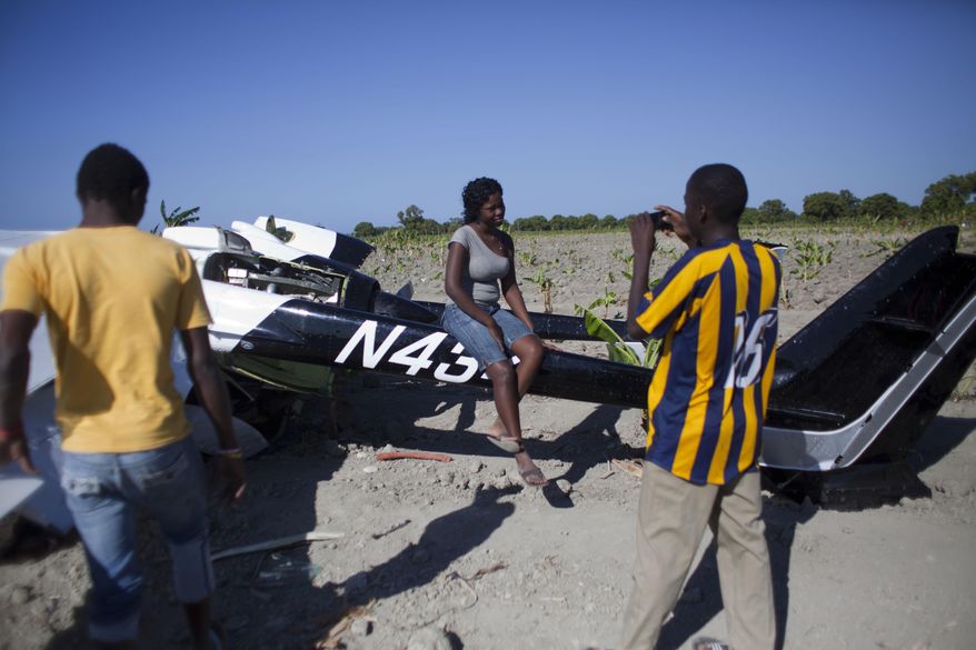A woman poses for a photo while sitting on a Cessna Super Skymaster that made an emergency landing the night before in a field just outside Cabaret, a coastal town northwest of Port-au-Prince, Haiti, Thursday Jan. 30, 2014. Haitian police said on Thursday that the small plane piloted by a U.S. citizen suffered mechanical problems and made an emergency landing in the banana field. Police inspector Joachin Antoine said that pilot Practor Antoine was treated for unspecified injuries at a hospital in the capital. A passenger named John Michael was not injured. (AP Photo/Dieu Nalio Chery)