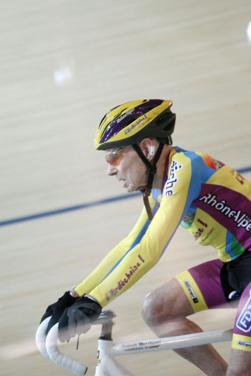 French cyclist Robert Marchand, aged 102, cycles in a bid to beat his record for distance cycled in one hour, at the velodrome of Saint-Quentin en Yvelines, outside Paris, Friday, Jan. 31, 2014. The 102-year-old broke his own world record in the over-100s category Friday, riding 26.927 kilometers (16.7 miles) in one hour, more than 2.5 kilometers better than his previous best time in the race against the clock two years ago. (AP Photo/Thibault Camus)