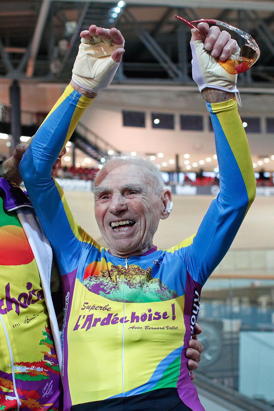 French cyclist Robert Marchand aged 102, celebrates after beating his record for distance cycled in one hour, at the velodrome of Saint-Quentin en Yvelines, outside Paris, Friday, Jan. 31, 2014. The 102-year-old broke his own world record in the over-100s category Friday, riding 26.927 kilometers (16.7 miles) in one hour, more than 2.5 kilometers better than his previous best time in the race against the clock two years ago. (AP Photo/Thibault Camus)