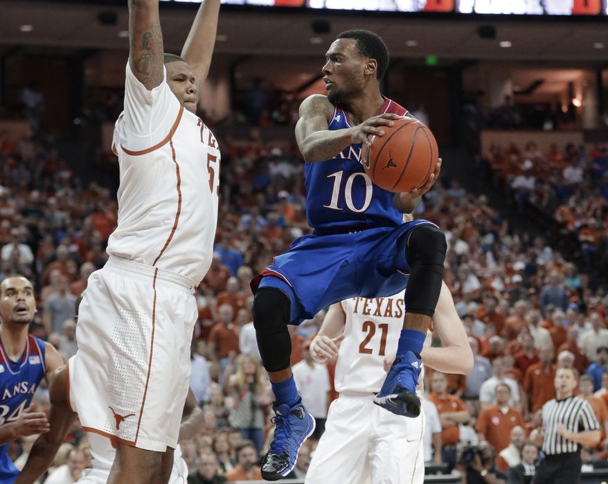 Kansas' Naadir Tharpe (10) looks to pass around Texas' Cameron Ridley (55) during the second half of an NCAA college basketball game, Saturday, Feb. 1, 2014, in Austin, Texas. Texas won 81-69. (AP Photo/Eric Gay)
