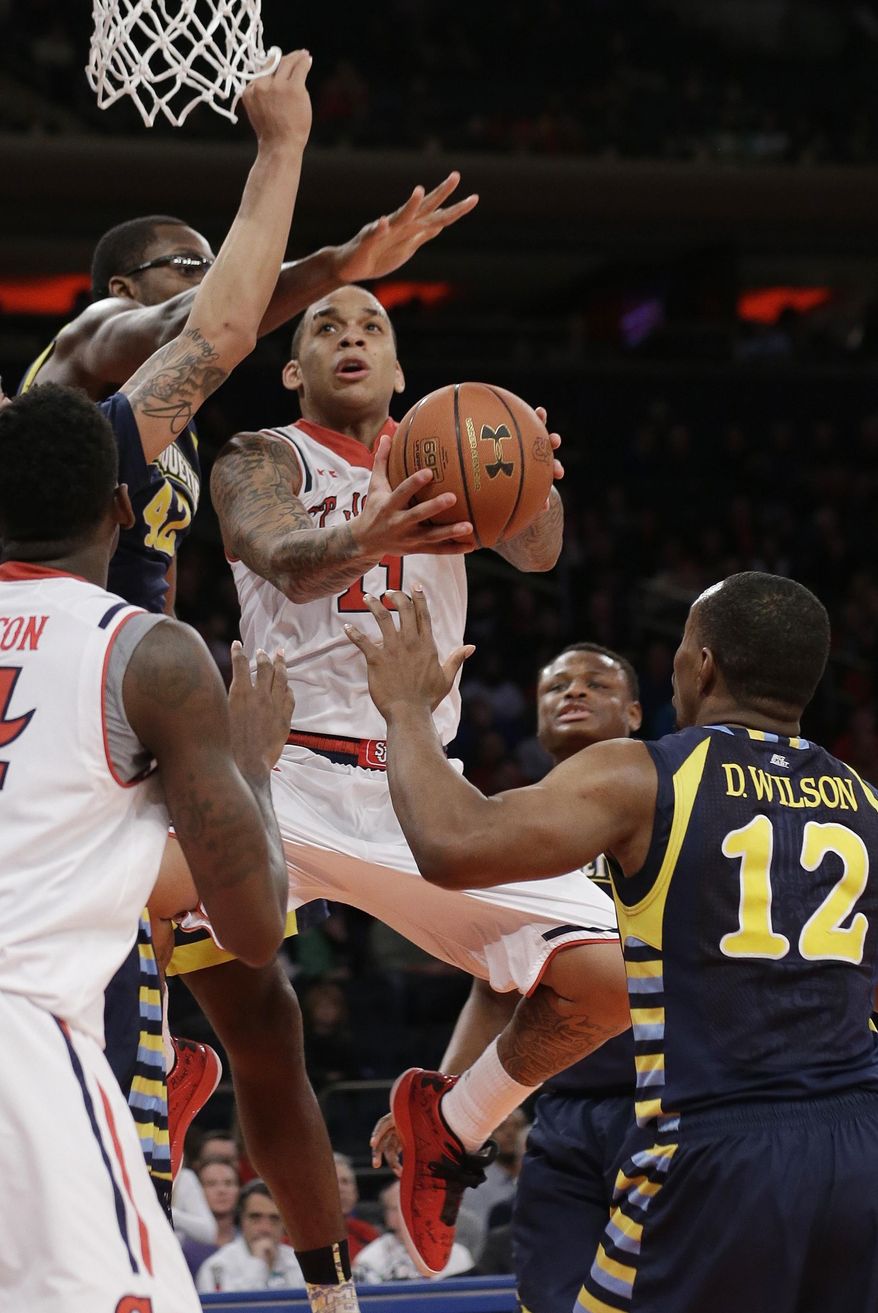 St. John's' D'Angelo Harrison (11) drives past Marquette's Chris Otule (42) and Derrick Wilson (12) during the second half of an NCAA collage basketball game Saturday, Feb. 1, 2014, in New York. (AP Photo/Frank Franklin II)