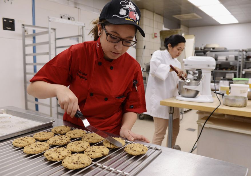 In this Jan. 15, 2014, 2014 photo, culinary student Marisa Marquez places cookies on a cooling rack in the Harper College kitchen in Palatine, Ill. Marquez, who describes herself as a "huge" Disney fan, has watched TV programs which show pastry chefs and cooks working in the Disney kitchen and hopes to tour the Grand Floridian kitchen sometime soon. (AP Photo/Daily Herald, Joe Lewnard) MANDATORY CREDIT, MAGS OUT