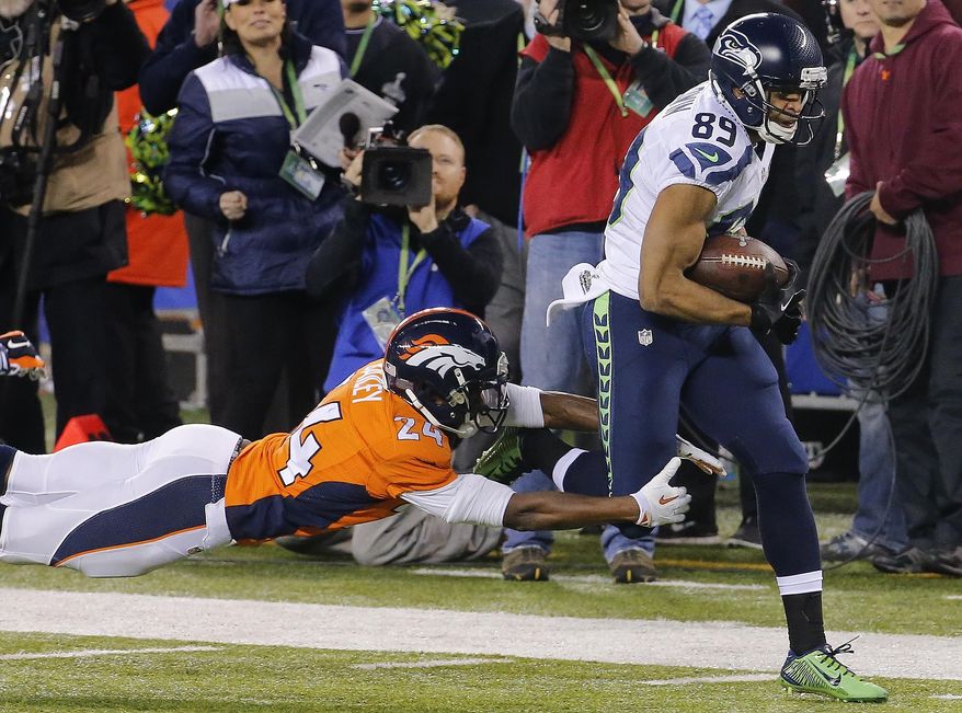 Denver Broncos cornerback Champ Bailey (24) reaches for Seattle Seahawks wide receiver Doug Baldwin (89) during the first half of the NFL Super Bowl XLVIII football game Sunday, Feb. 2, 2014, in East Rutherford, N.J. (AP Photo/Matt York)