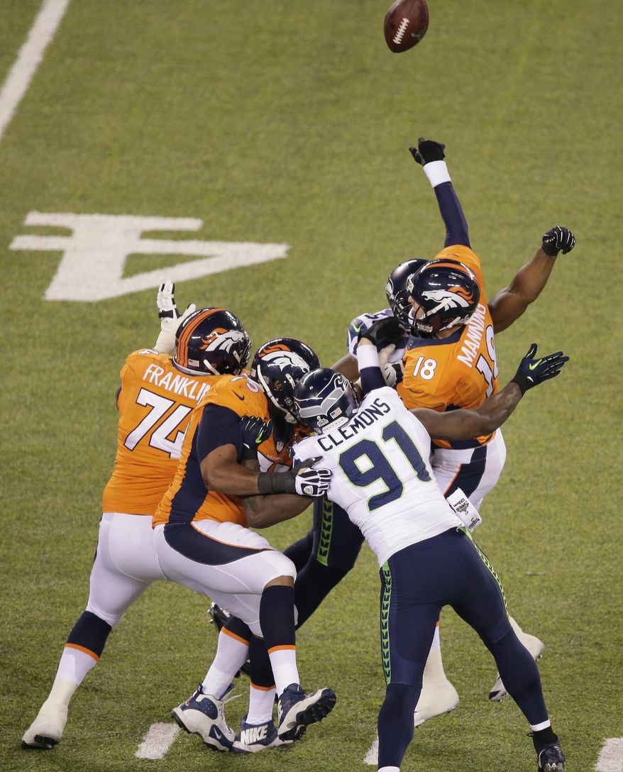 Denver Broncos' Peyton Manning is hit by Seattle Seahawks' Cliff Avril (56) and Seattle Seahawks' Chris Clemons (91) during the first half of the NFL Super Bowl XLVIII football game Sunday, Feb. 2, 2014, in East Rutherford, N.J. Manning was charged with an interception on the play. (AP Photo/Charlie Riedel)