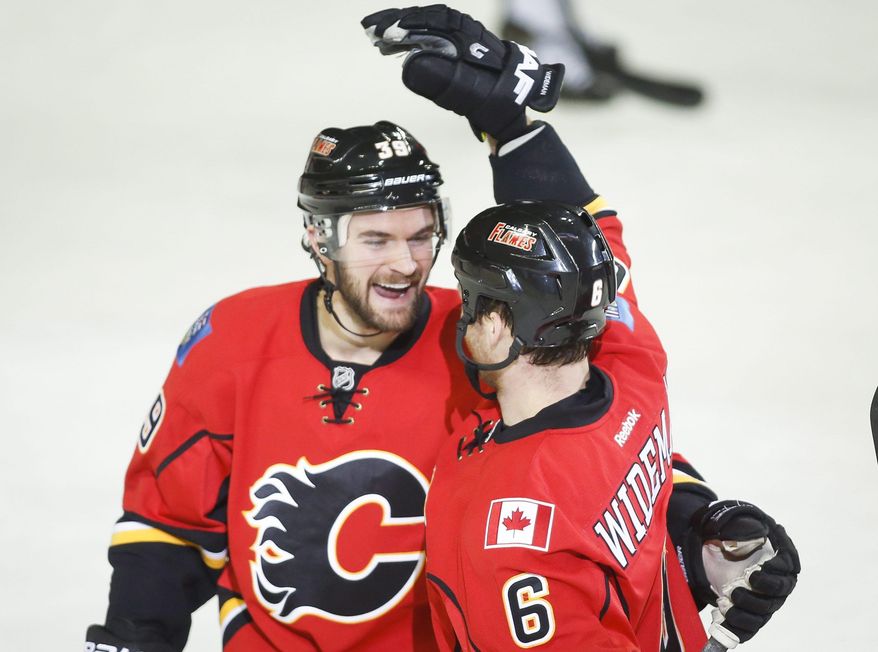 Calgary Flames' Dennis Wideman, right, celebrates his goal with teammate TJ Galiardi during second period of an NHL hockey game in Calgary, Alberta, Saturday, Feb. 1, 2014. (AP Photo/The Canadian Press, Jeff McIntosh)