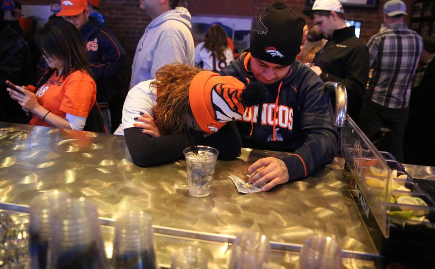 Denver Broncos fans Tatiana Bohorquez and Jorge Puerto look away from the TV while watching their team fall behind the Seattle Seahawks during the second half of the Super Bowl, inside Jackson's, a sports bar and grill in Denver, Sunday, Feb. 2, 2014. The Seahawks won 43-8. (AP Photo/Brennan Linsley) **FILE**