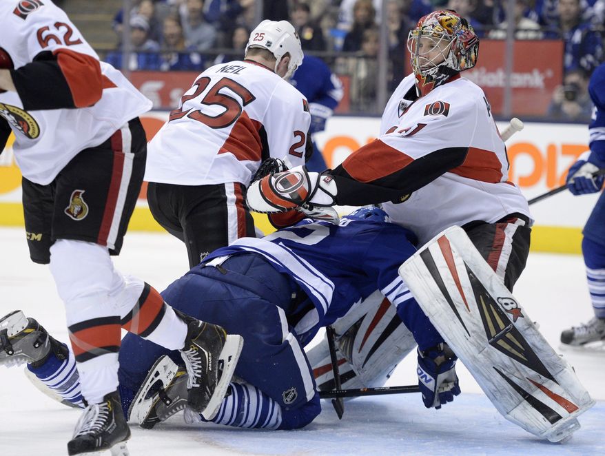 CORRECTS FROM THIRD TO SECOND PERIOD- Ottawa Senators' Chris Neil (25) checks Toronto Maple Leafs' Mason Raymond (12) into Senators goalie Craig Anderson during the second period of an NHL hockey game in Toronto, Saturday, Feb. 1, 2014. (AP Photo/The Canadian Press, Frank Gunn)
