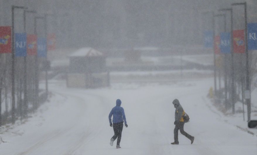 A jogger and pedestrian cross a snowy Jayhawk Boulevard on the University of Kansas campus in Lawrence, Kan., Tuesday, Feb. 4, 2014. A major winter storm brought heavy snow Tuesday across much of Kansas, threatening the Topeka area with up to a foot of snow. Kansas government ground to a halt as lawmakers postponed legislative work and state departments urged their workers to stay home. Schools throughout the state canceled classes. (AP Photo/Orlin Wagner)