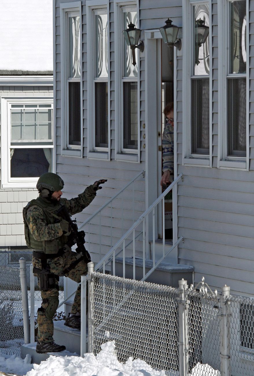 A member of law enforcement, left, checks in with a resident, Tuesday, Feb. 4, 2014, in the area of Richard and Hemlock streets in Dartmouth, Mass., during a standoff with a man who had made threats “to shoot up” Roger Williams University's campuses in Bristol and Providence, R.I. Dartmouth Police Chief Timothy Lee said the man surrendered peacefully after a six-hour standoff at his home. (AP Photo/The Standard-Times, John Sladewski)