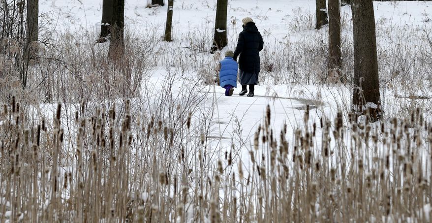A woman and child take a walk at the Cleveland MetroParks North Chagrin Reservation Tuesday, Feb. 4, 2014, in Willoughby Hills, Ohio. Winter-weary Ohioans are bracing for what could be the biggest snowstorm of the season so far. Forecasters say most of the state could end up with 6 to 10 inches of snow on the ground by the time it's over. (AP Photo/Tony Dejak)