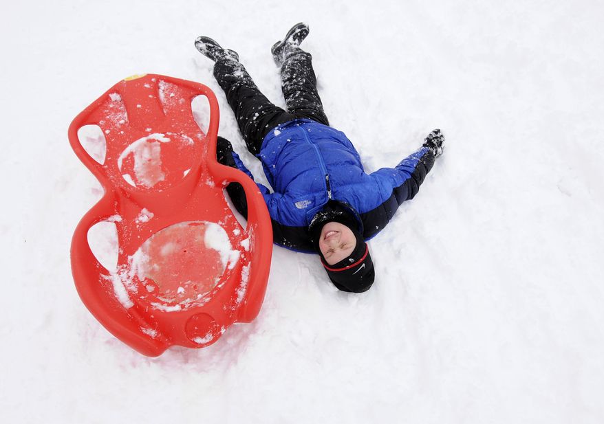 Ben Gerhard, 10, of Shillington, Pa. laughs and lays in the snow after flying off his sled in Shillington Park, Monday, Feb. 3, 2014. A winter storm drops more than six inches of snow on Berks County. (AP Photo/Reading Eagle, Jeremy Drey)