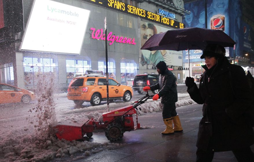 A worker uses a snow blower to clear a sidewalk in New York's Times Square, Wednesday, Feb. 5, 2014. While New York City public schools remain open, there are transit delays in the area's subways, commuter rail lines and airports. (AP Photo/Mark Lennihan)