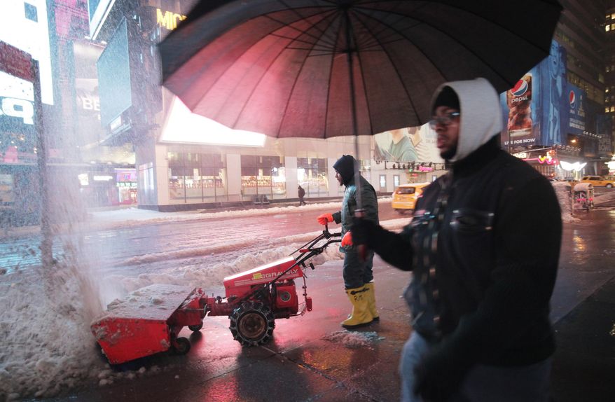 A worker uses a snow blower to clear a sidewalk in New York's Times Square, Wednesday, Feb. 5, 2014. While New York City public schools remain open, there are transit delays in the area's subways, commuter rail lines and airports. (AP Photo/Mark Lennihan)