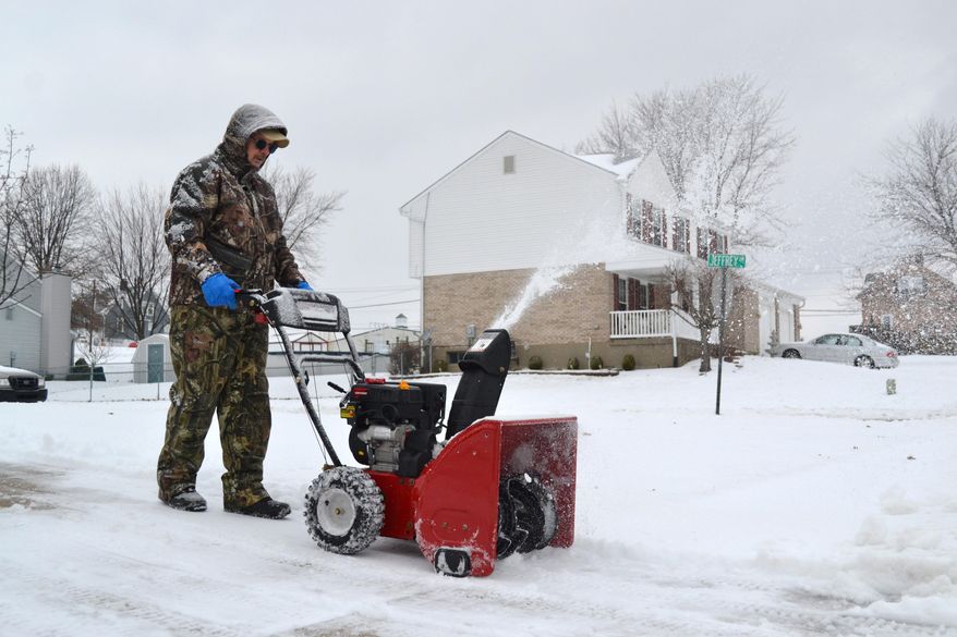 Dennis Reynolds uses a snow blower to clear his neighbor's driveway in Hebron, Ky., on Wednesday, Feb. 5, 2014. An icy snow covered the Cincinnati and northern Kentucky region overnight, leaving four inches or more in some areas. (AP Photo/Dylan Lovan)