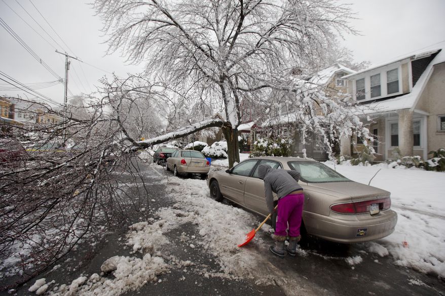 A woman clears snow near a downed tree limb after a winter storm Wednesday, Feb. 5, 2014, in Philadelphia. Icy conditions have knocked out power to more than 200,000 electric customers in southeastern Pennsylvania and prompted school and legislative delays as well as speed reductions on major roadways. (AP Photo/Matt Rourke)